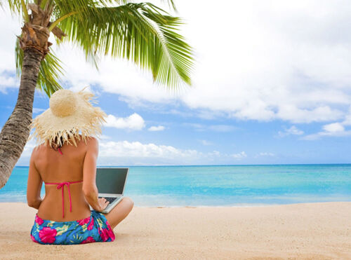 Woman uses laptop on beach.